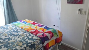 Un dormitorio con una cama, un televisor montado en la pared y un cuadro.