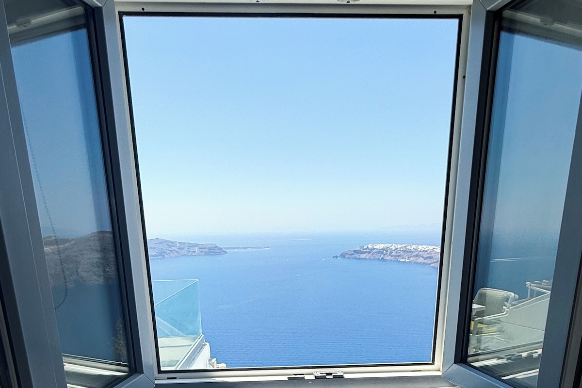 A bathtub with a view of the sea through a window.