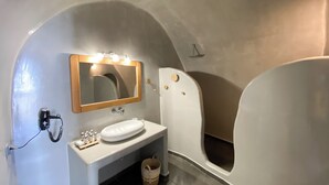 A bathroom with a sink, mirror, and two bathtubs. - Esmi Suites Santorini (Imerovigli)