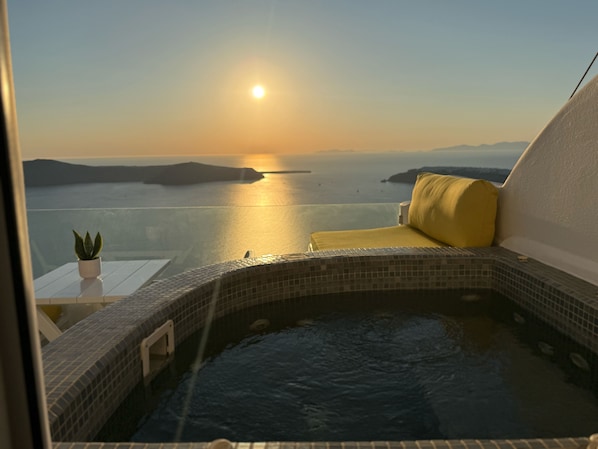 A hot tub with a view of the sea at sunset.