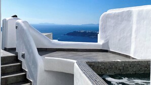 A white-walled building with a view of the sea and distant mountains. - Esmi Suites Santorini (Imerovigli)