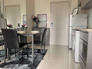 Une cuisine moderne équipée d’un lave-linge, un coin repas avec des chaises et une table, et une porte donnant sur une autre pièce.