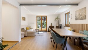 A modern living room with a sofa, dining table, and chairs. There is a sliding glass door leading to a balcony. - Apartment “Am Brändbach” with Private Terrace, Garden, and Wi-Fi (Bräunlingen)