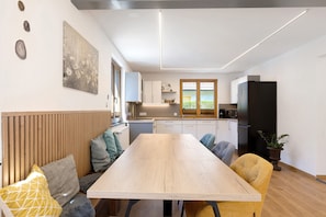 A modern kitchen with wooden cabinets, a black refrigerator, and a window with a view. - Apartment “Am Brändbach” with Private Terrace, Garden, and Wi-Fi (Bräunlingen)