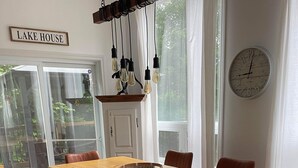 A dining area with a wooden table, six chairs, a hanging light fixture, a clock, and a sign that reads 'LAKE HOUSE'. - Chalet La Félicita, enchanting waterfront. (Saint-Adolphe-d'Howard)