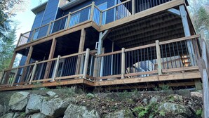 A multi-story building with a wooden deck and balconies. - Chalet La Félicita, enchanting waterfront. (Saint-Adolphe-d'Howard)