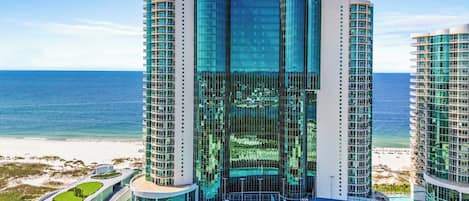 A modern hotel with a curved facade, multiple balconies, and a pool area.