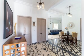 A hallway with patterned flooring, a dining area with a round table and chairs, and a living room with a sofa and curtains. - Villa Sans Vis à Vis, Jacuzzi 38°, Hammam, Piscine & WIFI (Marrakech)