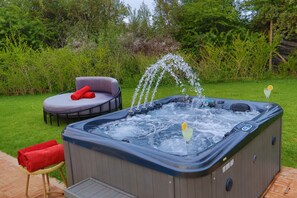 A hot tub with water jets, a lounge chair, and a small table with towels. - Villa Sans Vis à Vis, Jacuzzi 38°, Hammam, Piscine & WIFI (Marrakech)