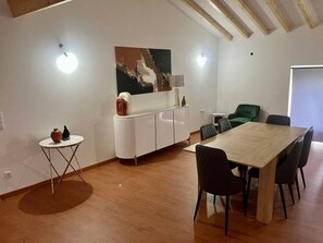 A dining area with a wooden table and chairs, a small round table with a vase, a cabinet, and a painting on the wall. - Relaxing refuge by the River Alva (Santo António de Alva)