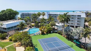 Hotel com piscina, quadra de tênis e vista para o oceano.