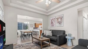 Een woonkamer met een bank, salontafel en een eetgedeelte met stoelen en een tafel.