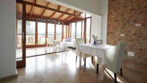 A dining area with a table and chairs, a stone wall, and a view of the outdoors. - Serene Mallorca Sanctuary for Yoga Retreats & Events (Manacor)