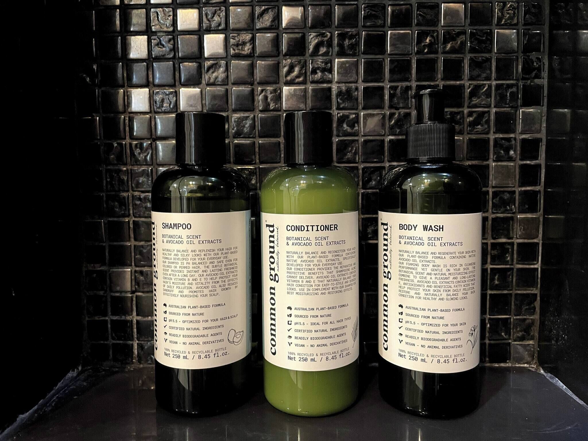 Three bottles of hair care products against a tiled wall.