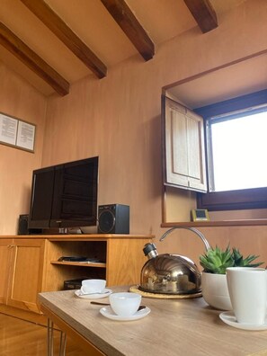 A kitchen with wooden cabinets, a built-in TV, a kettle, and a window with a view.