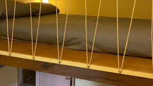 A bunk bed with a wooden frame and a lower bed, a bedside table, and a chair in a room with yellow walls. - El Xiprer - El Refugi de la Vall de Biert Total disconnection 25 min from Girona (CANET D'ADRI)