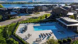 A resort with a swimming pool, lounge chairs, and a view of mountains and a lake. - Edgewater 103B | 1 Bedroom Suite | Pool | Pineview (Huntsville)