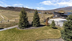 A modern building with a flat roof, surrounded by a well-maintained lawn and two evergreen trees. - Edgewater 103B | 1 Bedroom Suite | Pool | Pineview (Huntsville)