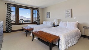 A hotel room with two beds, a bench, a desk, and a view of mountains. - Edgewater 103B | 1 Bedroom Suite | Pool | Pineview (Huntsville)