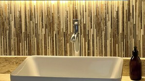 Een badkamer met een witte wastafel, een spiegel en een wand met een houten structuur.