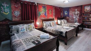 Una habitación con dos camas de madera, cortinas rojas y una pared de ladrillo decorada con varias banderas.
