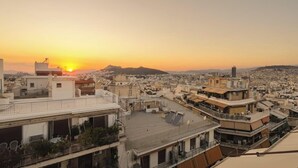 A cityscape at sunset with multiple buildings and a clear sky. - Kristy's 360 view elegant rooftop flat (Zografou)