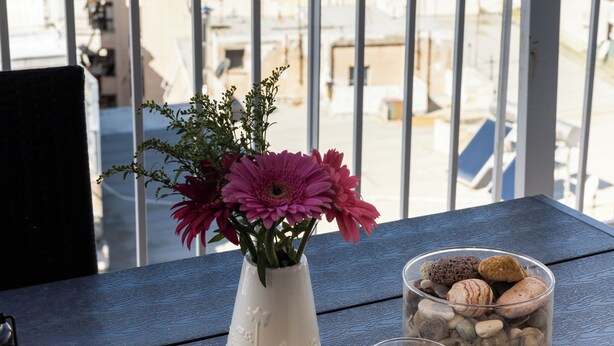 A balcony with a view of a cityscape, a vase with flowers, and a candle. - Kristy's 360 view elegant rooftop flat (Zografou)