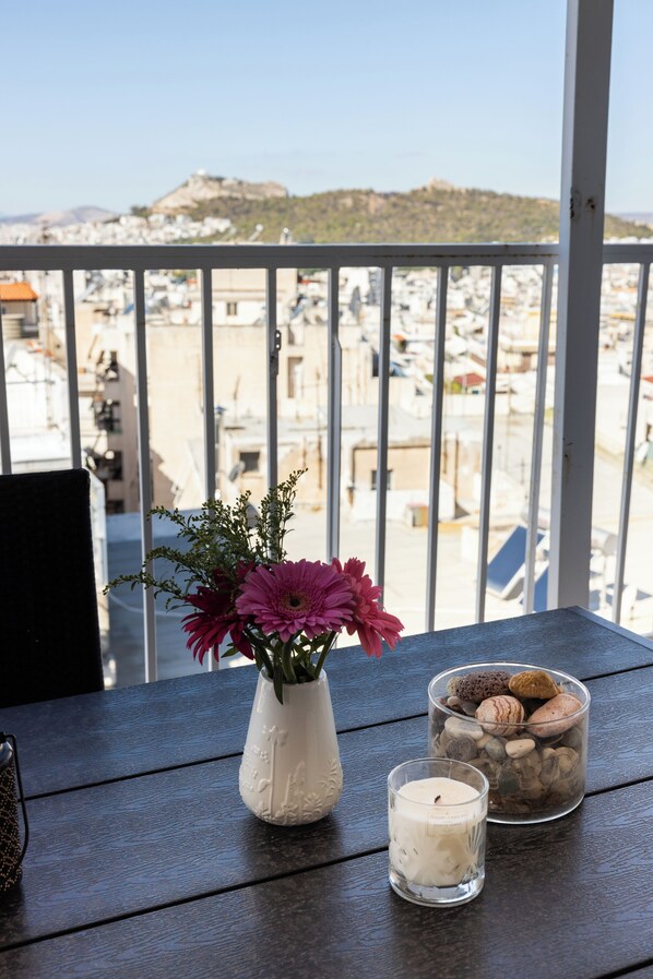 Ein Balkon mit Blick auf eine Stadtansicht, eine Vase mit Blumen und eine Kerze.
