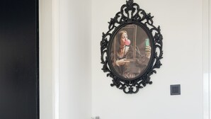 A room with a large ornate chair, a small table with a vase of flowers, and a framed picture on the wall. - Kristy's 360 view elegant rooftop flat (Zografou)