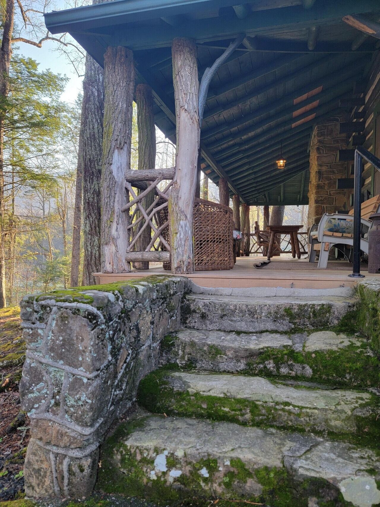 A rustic wooden structure with stone steps leading up to a covered area with seating.. Historic Cabin Retreat w/ Unique Mountain History
