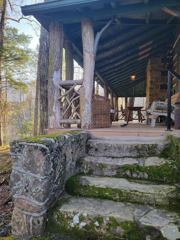 A rustic wooden structure with stone steps leading up to a covered area with seating.