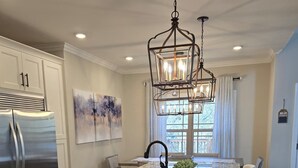 A kitchen with a large island, stainless steel refrigerator, pendant lighting, and a window with curtains. - Lake Days & Nashville Nights — Private Dock, Game Room & Fire Pit - Room for 12 (Gallatin)