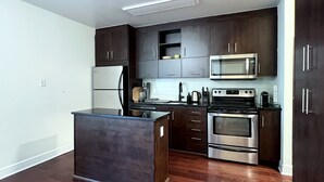 A modern kitchen with dark wood cabinets, stainless steel appliances, and a central island. - 2-bed, 2-bath spacious condo one block from St Lawrence market (Toronto)