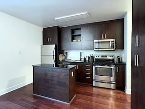 A modern kitchen with dark wood cabinets, stainless steel appliances, and a central island.