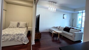 A modern living room with a sofa, a coffee table, a flat-screen TV, and a wooden cabinet. - 2-bed, 2-bath spacious condo one block from St Lawrence market (Toronto)