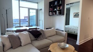 A modern living room with a sofa, a round coffee table, and a bookshelf. - 2-bed, 2-bath spacious condo one block from St Lawrence market (Toronto)