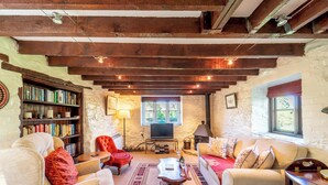 Un salón acogedor con chimenea, televisor, estantería y asientos cómodos.