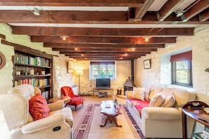 Ein gemütliches Wohnzimmer mit Kamin, Fernseher, Bücherregal und bequemen Sitzmöglichkeiten.