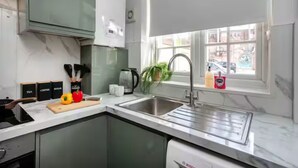 Een moderne keuken met een spoelbak, aanrecht en kastjes.
