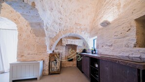 A kitchen with stone walls, a wooden counter, and a rustic cabinet. - TD Trullo Lumina Boutique Luxury Trulli with Pool (Ostuni)