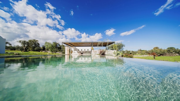 En klar swimmingpool med en pergola i baggrunden.