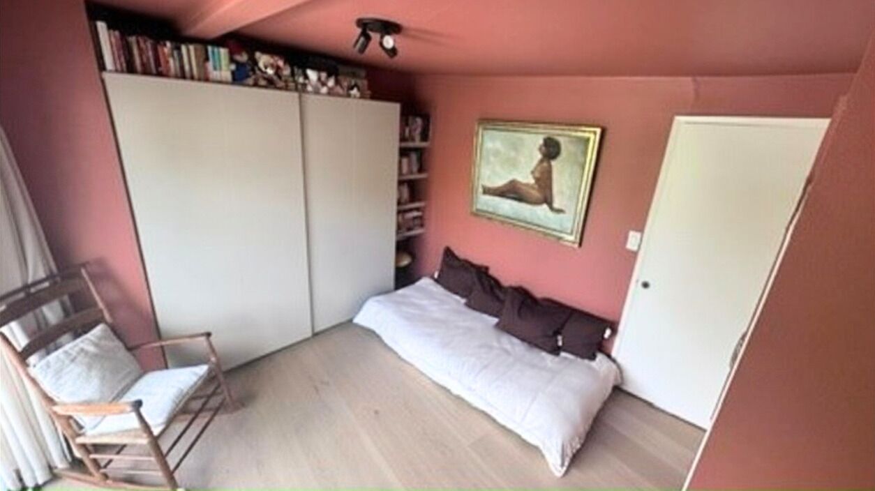 A bedroom with a bed, a chair, a wardrobe, and a painting on the wall.