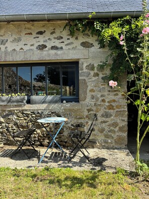 A stone building with a window, a small table, and a chair. - COTTAGE IN A TYPICAL FISHERMEN'S VILLAGE 5 mn from the beach (Blainville-sur-Mer)
