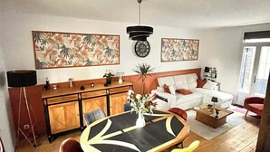 A modern living room with a dining area, a sofa, a coffee table, and a kitchen area with a cabinet and a plant. - Charming house (Béthisy-Saint-Martin)