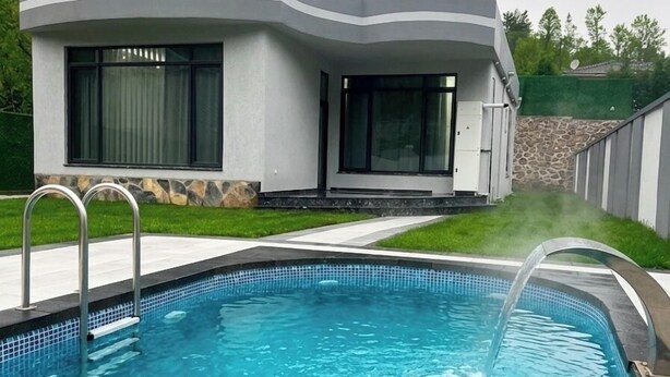 Ein modernes Haus mit Swimmingpool, Satellitenschüssel und einer Steinmauer.