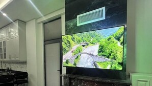 Eine moderne Küche mit großem Flachbildfernseher über einem Kamin, einer Kücheninsel mit Spüle und Schränken.
