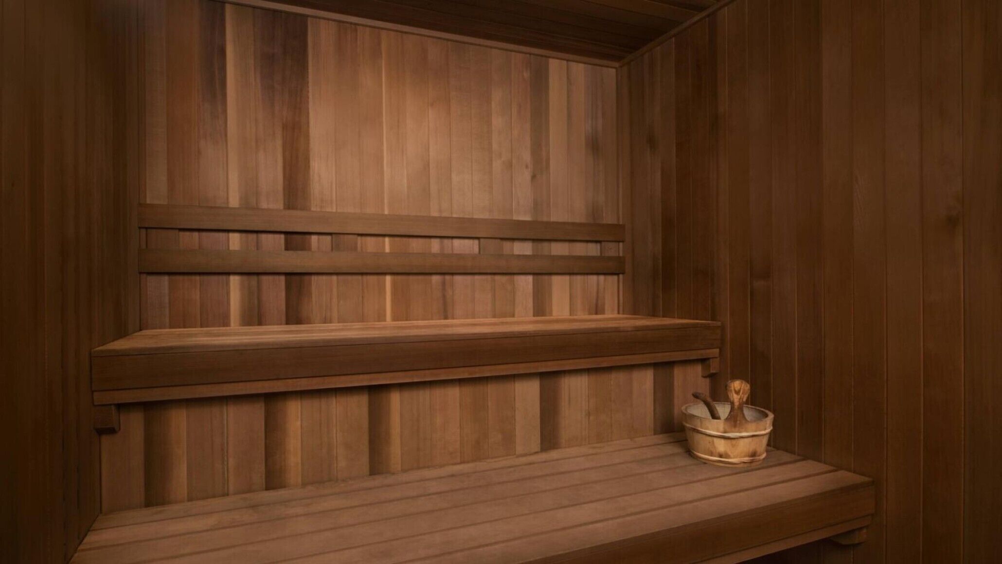 Een houten sauna met een bankje en een houten emmer.