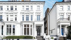 A row of white townhouses with bay windows, a blue door, and a small balcony. - Elegant 2 bed near Hampstead & Camden (London)