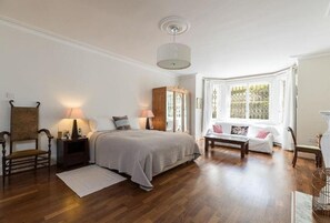 Ein Schlafzimmer mit einem Bett, Nachttischen, einer Fensterbank und Holzdielen.