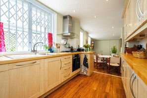 Eine moderne Küche mit Holzausbau, einer zentralen Kochinsel und einem Essbereich mit Tisch und Stühlen.